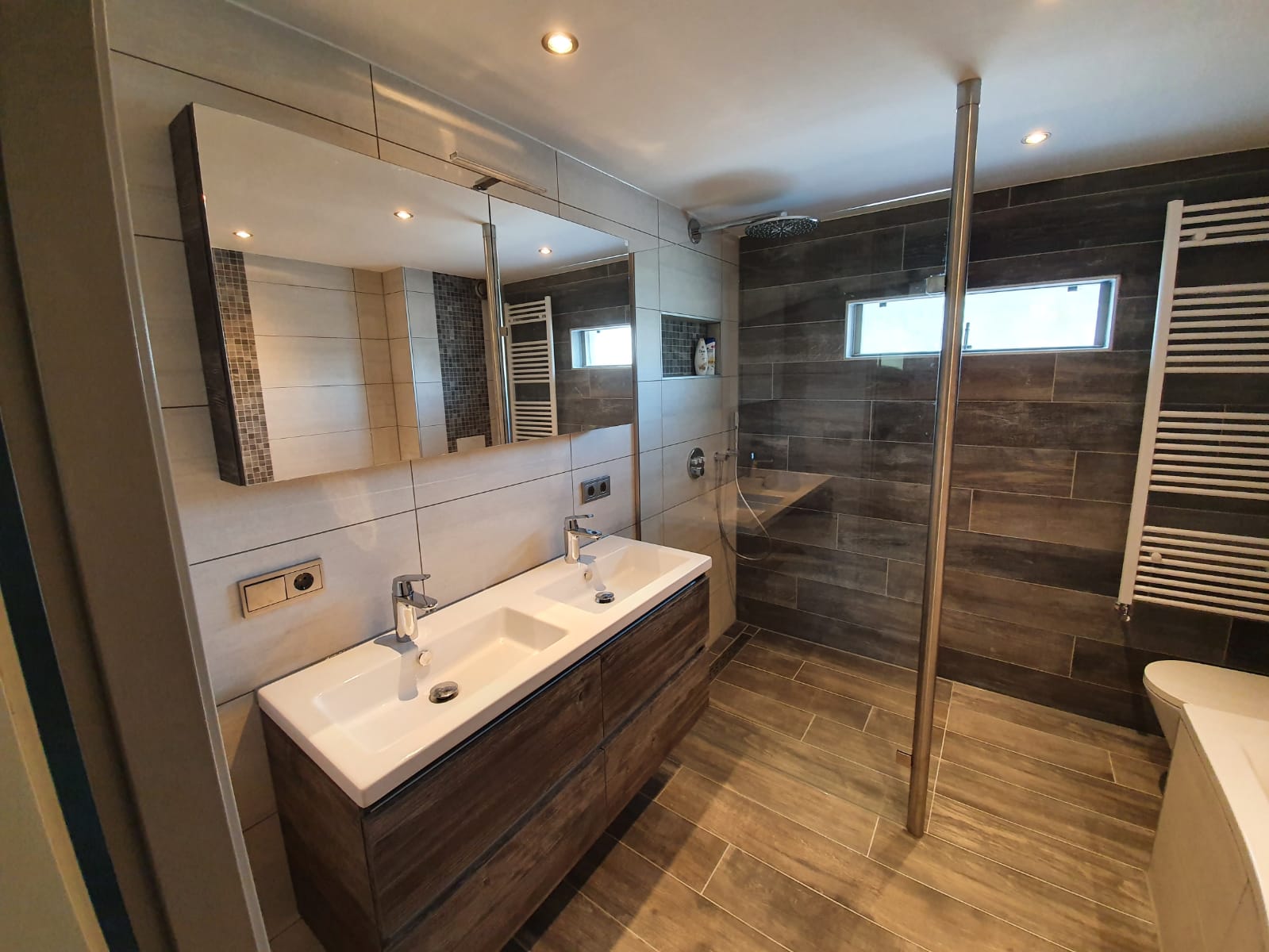 Ruime badkamer met houtlook tegels, dubbel wastafelmeubel, bad en inloopdouche