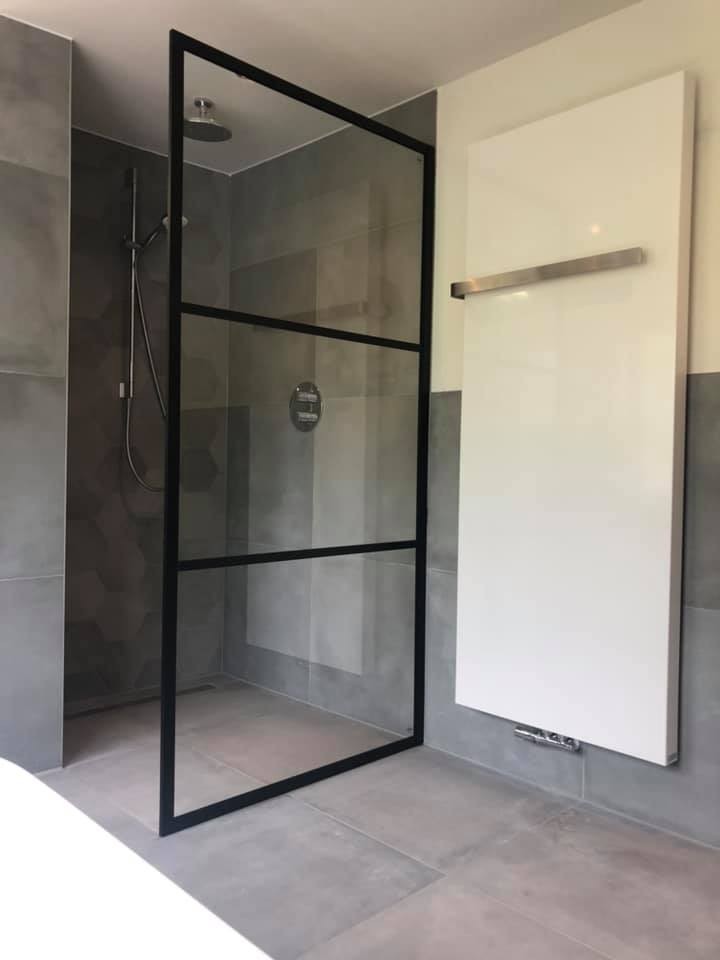 Douchewand met zwart stalen frame naast een witte designradiator